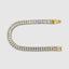 Yellow gold baguette tennis bracelet reflecting studio light, detail shot
