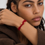 DVNCI red evil eye protection bracelet silk cord gold tips catching warm light
